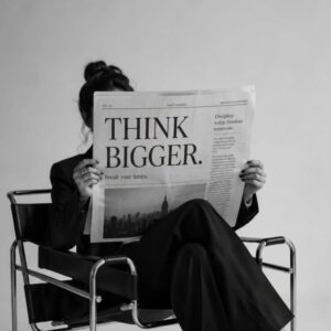 Woman reading a newspaper with the headline 'Think Bigger' representing business growth and digital marketing. Business growth concept by a freelance digital marketer in Kerala